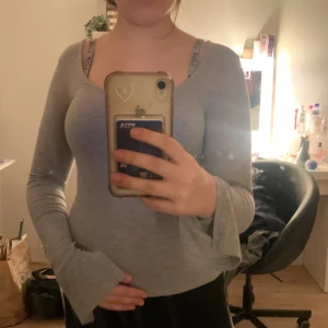 Grå långärmad topp från Gina Tricot - Säljer en stilren grå långärmad topp från Gina Tricot. Toppen har en enkel design med en rund halsringning och är perfekt för vardagsbruk. Den är tillverkad i ett mjukt och bekvämt material.