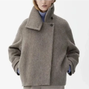 Beige ullkappa - Snygg och stilren beige kappa i ull med hög krage och knappar. Perfekt för kyliga dagar med sin oversized passform och långa ärmar. En tidlös klassiker för garderoben.