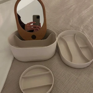 Vit förvaring med spegel - Praktisk vit smyckes/sminkförvaring med inbyggd spegel och flera fack för organisering. Perfekt för att hålla ordning på dina smycken och accessoarer. Stilren design som passar i alla rum.