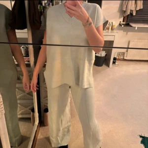 Set väst & byxor - Snygga ljusa byxor med slits vid anklarna. De har en loose passform och är perfekta för en avslappnad stil. Byxorna är högmidjade och har en mjuk och bekväm känsla.
