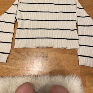 Vit och svart randig tröja från Zara - Säljer en stilren vit tröja från Zara med svarta ränder. Tröjan är ribbad och har långa ärmar, perfekt för en avslappnad look. Passar bra till både jeans och kjol!