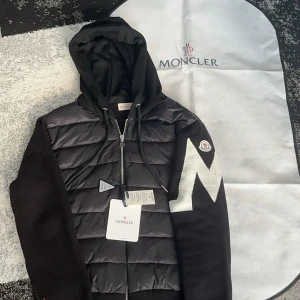 Moncler Cardigan  - Säljer denna fina cardigan med ett stort M på vänstra armen, jättefin och unik. Skicket är nytt, säljer den då jag behöver pengar. Skriv för eventuella frågor. NFC finns!