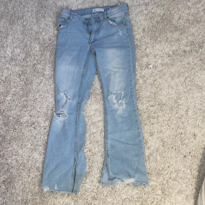 Ljusa jeans med slitningar från Zara - Säljer ett par ljusa jeans från Zara med coola slitningar på knäna. De har en bootcut-stil och är perfekta för en avslappnad look.säljer pågrund av fel storlek!❤️