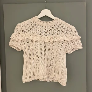 Beige stickad topp från Nisan - Charmig beige stickad topp från Nisan med korta ärmar och vackra spetsdetaljer. För liten för mig. 