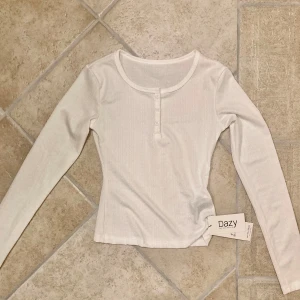 Vit långärmad topp  - Vit långärmad  topp i storlek XS med knappar. Toppen  är i gott skick då den aldrig är använd och har lapparna kvar. Klicka gärna på köp nu och meddela för eventuella frågor. :)