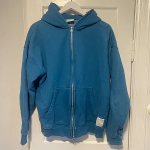 Blå hoodie från Pull&Bear - Säljer en blå ziphoodie från Pull&Bear med dragkedja och huva. Tröjan har långa ärmar och praktiska fickor framtill. Mycket bra skick. Storlek s-m men sitter som M