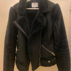 Svart pälsjacka från Dorothy Perkins - Snygg svart pälsjacka från Dorothy Perkins med dragkedja och långa ärmar. Perfekt för att hålla sig varm under kyliga dagar. Obs inte äkta päls