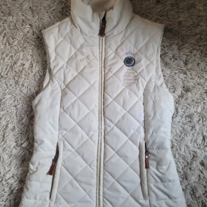 Vit quiltad väst från HV Society - Helt ny och aldrig använt. Man kan göra midjan större eller mindre. Väldigt fin men passade inte.