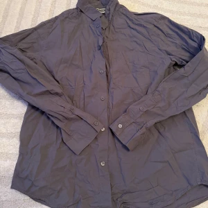 Grå skjorta från Weekday - Snygg grå skjorta från Weekday i storlek medium. Skjortan har långa ärmar och knappar framtill. Perfekt för en stilren look.