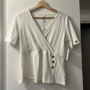 Vit omlottopp från Chiara Forthi - Vit topp från Chiara Forthi som är helt oanvänd. Den har en fläck på baksidan av armen från påsen som den har legat i men det går nog bort i tvätten, men därför är priset så lågt. 