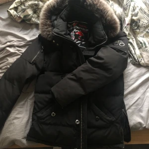 Mose knuckles jacka  - Snygg svart dunjacka från Mountain Hardwear med pälsdetaljer på huvan. Jackan har dragkedja och knappar framtill samt flera praktiska fickor. Perfekt för kalla dagar dragkedjan där nere har gått av men andra sidan är hel men Inge man stör sig på👍 titta alla bilderna
