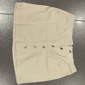 Vit kjol med knappar  - Snygg vit kortkjol från med knappar. Kjolen är aldrig använd så den är i mycket bra skick. Har ingen aning vart den är köpt. Skriv för mer bilder eller andra frågor :) 