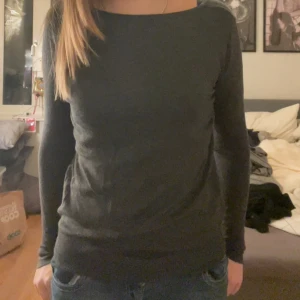 Mörkgrå tröja från Åhléns - Säljer en stilren mörkgrå tröja från Åhléns. Tröjan har en enkel design med långa ärmar och en rund halsringning. Perfekt för en avslappnad look.