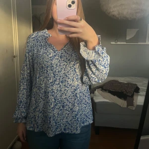 blåblommig blus - Jättefin blus med blåa blommor, använd 1 gång men kommer tyvärr inte till användning längre. Perfekt till vardags med jeans eller till sommaren/våren med en fin kjol.