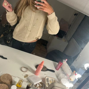 Beige stickad tröja - Säljer en mysig beige stickad tröja med kabelstickat mönster. Tröjan har långa ärmar och en croppad passform, perfekt för kyligare dagar. Passar bra till jeans eller kjol för en avslappnad look.