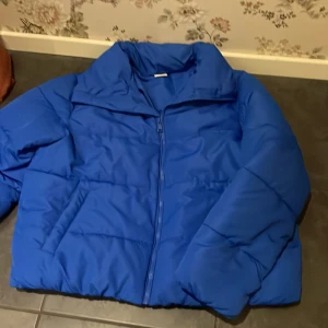 Blå pufferjacka - Säljer en snygg blå pufferjacka med dragkedja. Perfekt för kyliga dagar med sin vadderade design och höga krage.