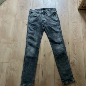 Grå jeans från Replay - Snygga grå jeans från Replay med en klassisk femficksdesign. De har en knappgylf och är i en stilren grå färg som passar till det mesta. Perfekta för en avslappnad look. Storlek w31 L34