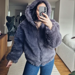 Grå pälsjacka från Weekday - Mysig grå pälsjacka från Weekday med huva och dragkedja. Perfekt för kyliga dagar när du vill hålla dig varm och stilren. Jackan har en fluffig textur och långa ärmar.