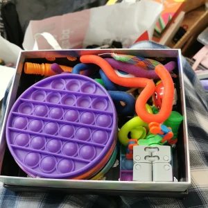 Fidget leksaker i en låda - En låda fylld med olika fidget toys. Finns allt mellan popits, monkey noodles, infinity cube, mm. Enda defekt är monkey noodlesna som är dammiga då allt har vart orört i nått år. VILL HELST FÅ BORT SÅ SNABBT SÅ MÖJLIGT DÅ JAG SNART FLYTTAR!! Pris kan diskuteras. 