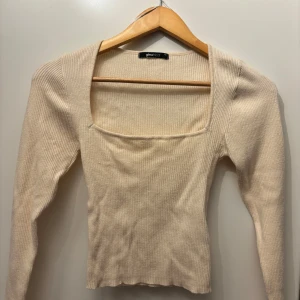Beige ribbad topp från Gina Tricot - Säljer en beige ribbad topp från Gina Tricot. Toppen har en fyrkantig urringning och långa ärmar, perfekt för alla typer av outfits✨
