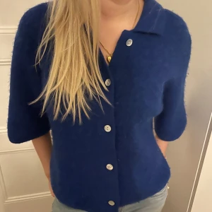 Blå kofta från & Other Stories - Säljer en snygg blå kofta från & Other Stories. Den har trekvartsärmar och knappar framtill. Perfekt för en stilren look.