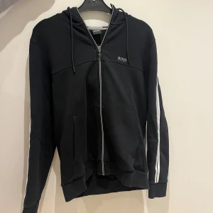 Svart mjukisaett från Hugo Boss - Säljer ett par svarta mjukisbyxor från Boss med vita ränder längs sidorna. Finns en kofta till byxorna om man vill köpa hela setet men kan också köpas separat. Pris kan diskuteras 