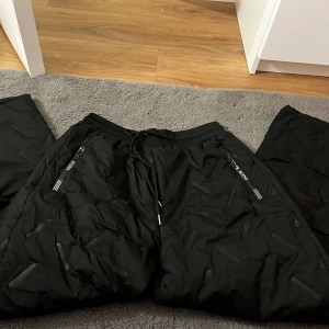 Svarta termobyxor med fleecefoder - Säljer ett par svarta termobyxor med mjukt fleecefoder. Byxorna har dragsko i midjan och praktiska fickor med dragkedja. Perfekta för kalla dagar.