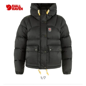 Svart dunjacka från Fjällräven - Snygg och varm svart dunjacka från Fjällräven med hög krage och justerbar huva. Jackan har praktiska fickor med knappar och dragkedja framtill. Det är den gamla modellen som har en puffig design 🥰 pris diskuteras 