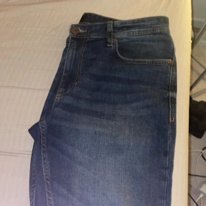 Blå jeans från Smog - Säljer ett par klassiska blå jeans från Smog. De har en rak passform med fem fickor och knappgylf. Perfekta för en avslappnad stil.storlek W32 L32