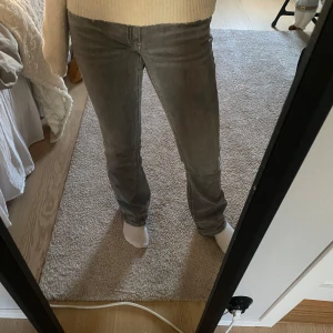 Grå jeans från Gina Tricot - Snygga grå jeans från Gina Tricot i en modern form. De har en normal passform och är perfekta för en snygg outfit. Jeansen har en knapp och dragkedja framtill samt fickor både fram och bak.