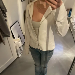 Vit huvtröja från Cool K - Säljer en vit huvtröja från Cool K med dragkedja och en snygg logga på bröstet. Tröjan har långa ärmar och en bekväm passform. Passar mig som bär S💗