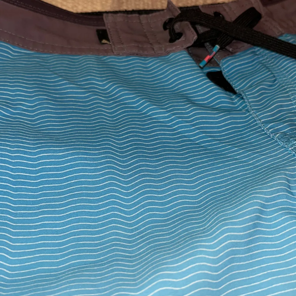 Säljer ett par snygga blå boardshorts från Quiksilver. De har ett coolt vågmönster och en svart dragsko i midjan. Perfekta för sommarens alla strandäventyr! 🏄‍♂️. Shorts.