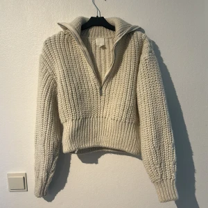 Beige stickad tröja med dragkedja - Säljer en supermysig beige stickad tröja med dragkedja. Perfekt för kyliga dagar med sin tjocka och varma design. Tröjan har långa ärmar och en hög krage som kan vikas ner. Den är i nyskick och knappt använd och passar perfekt för både höst och vinter. Lite croppad💕