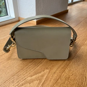 ATP ATELIER Assisi  - Fin Assisi shoulder bag från ATP Atelier. I Khakifärg, fint använt skick. Hela sömmar och läder o fräsch inuti. Lite småmärken på framsidan o karbinhakarna har ändrat lite färg. Nypris 4995:- för två år sedan. 2 olika remmar, kortbredare o lång smal.