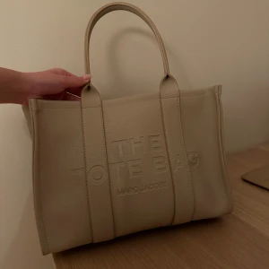 Marc Jacobs tote bag - Säljer min fina väska som är använd ett få antal gånger. Säljes då den inte kommer till användning längre. Väskan har en defekt på dragkedjan i en av facken i väskan, men det går att fixa, därav har jag gått ner väldigt mycket i pris! Väskan är perfekt som skolväska!