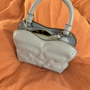 Handväska GANNI  - Säljer min väska från GANNI då den inte kommer till användning. Endast använd ett fåtal gånger och är därmed i mycket bra skick. Justerbart axelremsband ingår. Nypris 2795 kr 😊 