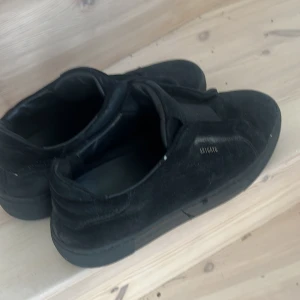 Svarta sneakers från Axel Arigato - Säljer ett par svarta sneakers från Axel Arigato. De är i mocka och har en stilren design utsn snörning, slip-ons. Perfekta för både vardag och fest!