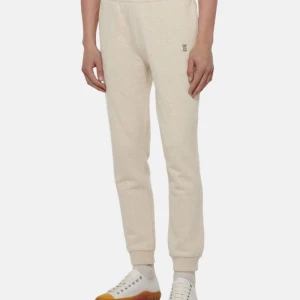 Beige burberry mjukisbyxor - Säljer ett par superbekväma beige burberry mjukisbyxor med en liten logotyp på sidan. De är perfekta för en chill dag hemma eller en avslappnad promenad. Byxorna har en elastisk midja och muddar vid bensluten för extra komfort. De är gjorda av mjuk bomull och har en normal passform. 