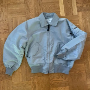Grå vintage bomberjacka i militärstil  - Supersnygg oversized bomberjacka i stl L. Den är i utmärkt skick bortsett från ett litet hål på framsidan. Jackan är av utmärkt kvalité och har en boxig passform. 