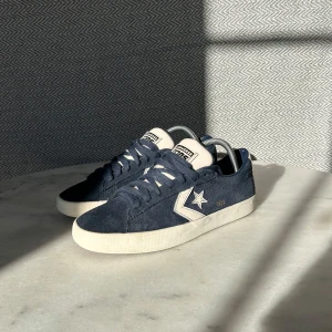 Blå sneakers från Converse - Snygga blå sneakers från Converse i mocka med vit sula och klassisk stjärnlogga på sidan. Skorna har snörning och en bekväm passform, perfekt för en avslappnad stil. Stolek:41 Skick: (9/10) 