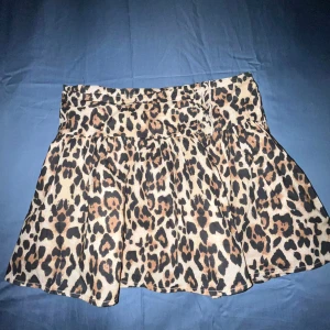 Leopardmönstrad kortkjol - Trendig leopardmönstrad kortkjol med en luftig passform. Perfekt för att ge din outfit en djärv touch. Kjolen har en bekväm midja och är lätt att matcha med olika toppar. (Helt oanvänd då lappen fortfarande är kvar)