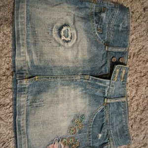 Jeanskjol - Trendig jeanskjol med slitna detaljer och vackra broderade blommor. 🌸 