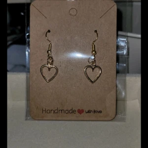Handgjorda hjärtformade örhängen - Charmiga handgjorda örhängen i guld med hjärtformad design. Perfekta för att ge en romantisk touch till din stil. Lätta och bekväma att bära.