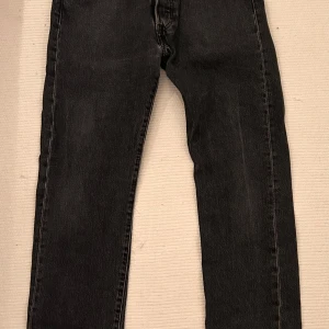 Svarta jeans från Levi's - Snygga svarta jeansbyxor från Levi's med klassisk femficksdesign och knappgylf. Perfekta för en stilren look I storlek 32/32. Finns utrymme för prutning 