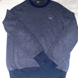 Mörkblå tröja från BOSS - Säljer en stilren mörkblå tröja från BOSS. Tröjan har en diskret logga på bröstet och är tillverkad i ett mjukt material. Perfekt för en avslappnad men ändå snygg look. Passar bra till jeans eller chinos.