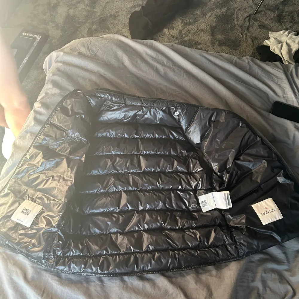Säljer en snygg svart dunväst från Moncler med dragkedja och hög krage. Västen har ett broderat Moncler-märke på bröstet och två praktiska fickor med dragkedja. Den är 100 procent äkta men ett litet hål som man knappt ser på vänster sida bröst. Den är i storlek 2 . Takit.