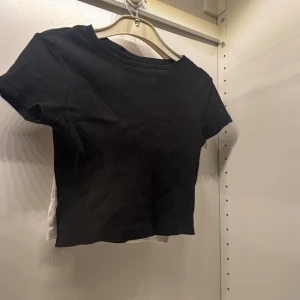 Svart croppad t-shirt - Säljer en svart croppad t-shirt med korta ärmar. Perfekt för en avslappnad stil. Har en till i vit om du vill köpa tillsamans eller vill ha en vit prig kan diskuteras