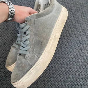Grå sneakers från Vagabond - Snygga grå sneakers från Vagabond i mocka med snörning. Perfekta för en avslappnad stil. Sulan är vit och har en klassisk design. Skorna är i storlek herr 42. Skick 6.5/10