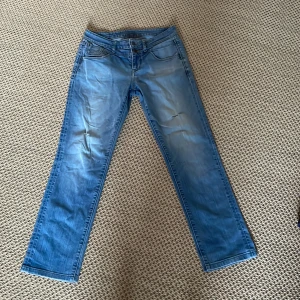 Blå jeans från Esprit - Snygga blå jeans från Esprit med rak passform. De har dubbla knappar i midjan och klassiska femficksdetaljer. Bakfickorna är dekorerade med ett stilrent broderi. Perfekta för en avslappnad stil.