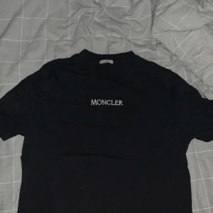 Moncler T-Shirt - Tja! Säljer en fin Moncler tisha. Den har fint tryck baktill med text framtill. Väldigt bra tisha. Perfekt för att ha under hoodien i vardagen. Hör av er vid frågor